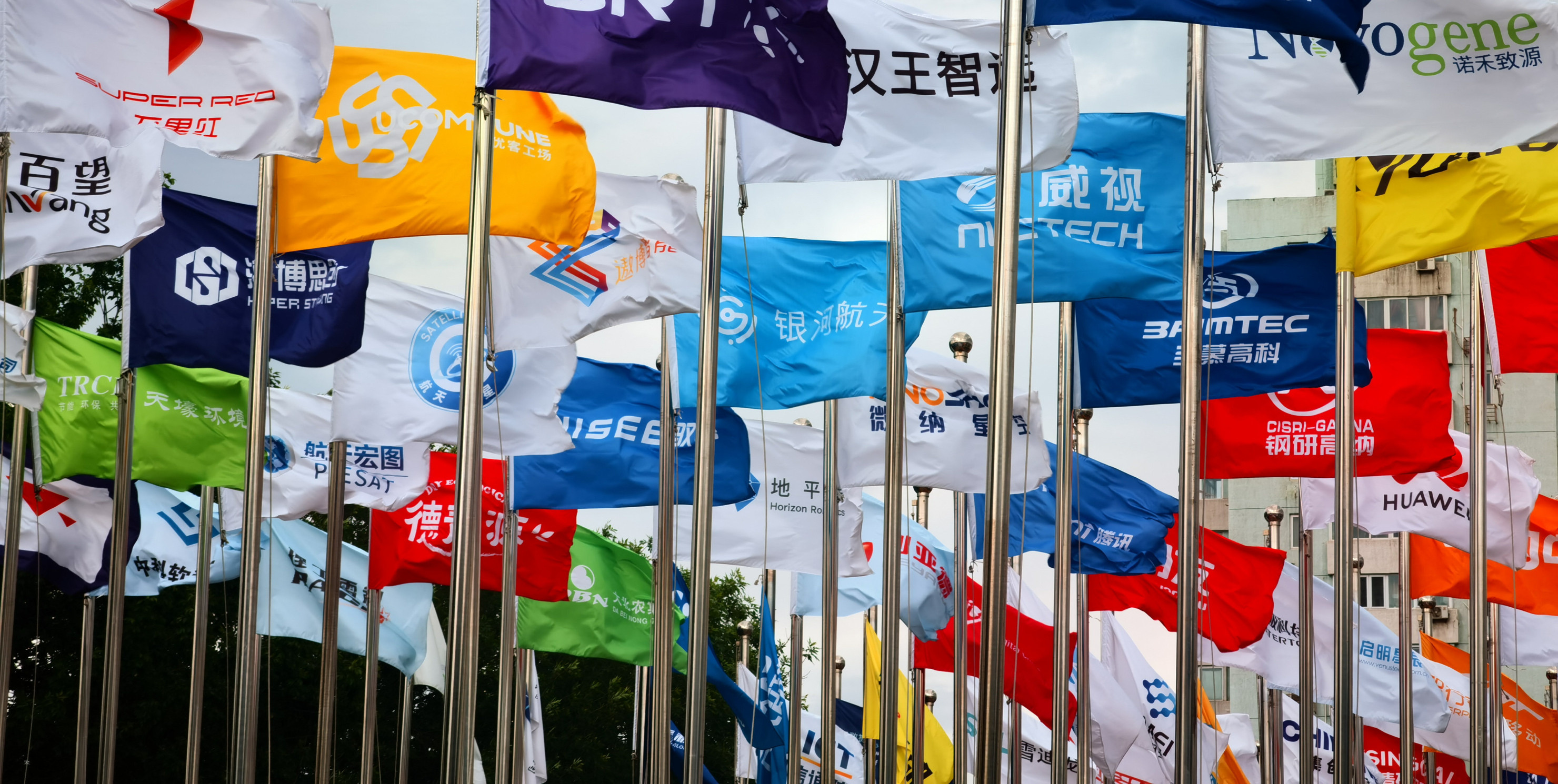 Factory flags of famous Chinese enterprises flutter in the wind under the blue sky in front of the square of the permanent site of the Zhongguancun Forum in Beijing, China, May 14, 2024.