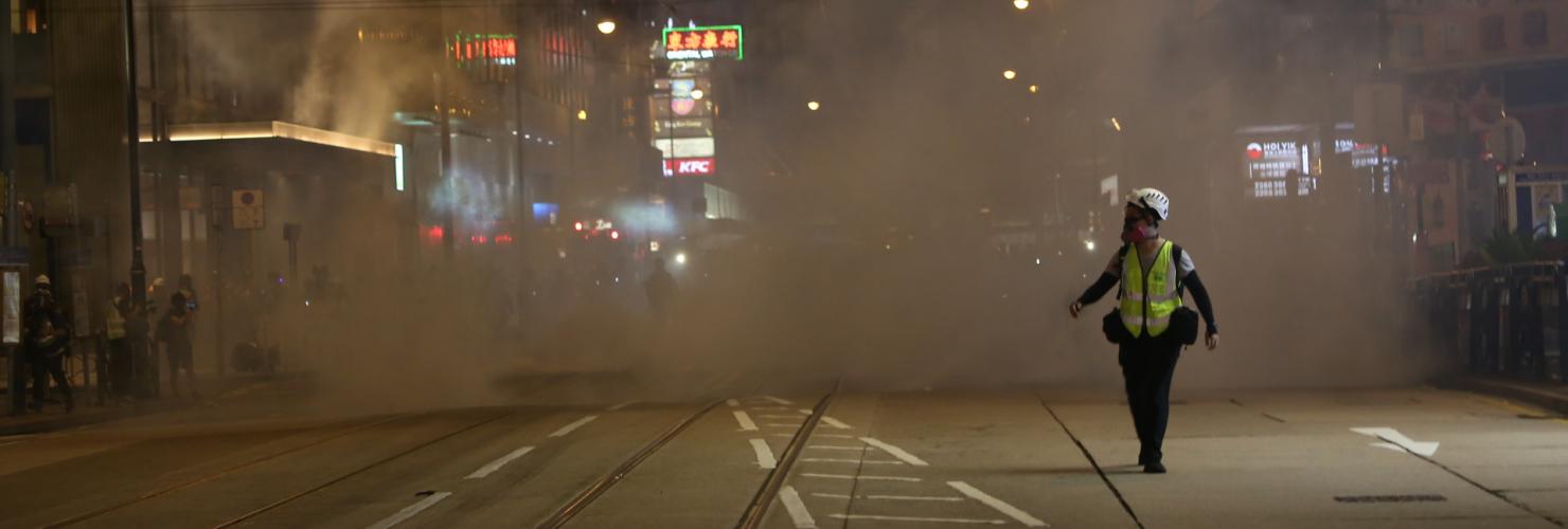 A journalist runs away from tear gas fired on the streets near Lan Kwai Fong, Hong Kong