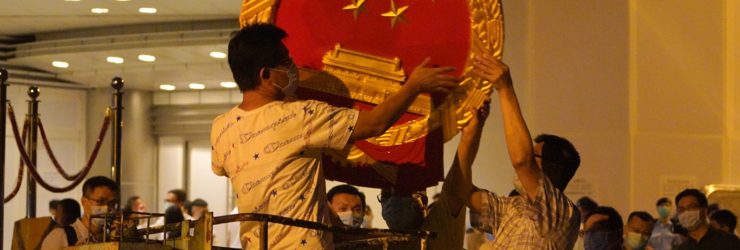 Workers place a national emblem outside the Metropark Hotel Causeway Bay