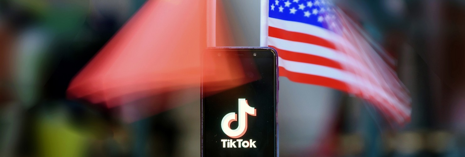 Smartphone showing the Logo of TikTok in front of US and Chinese flags