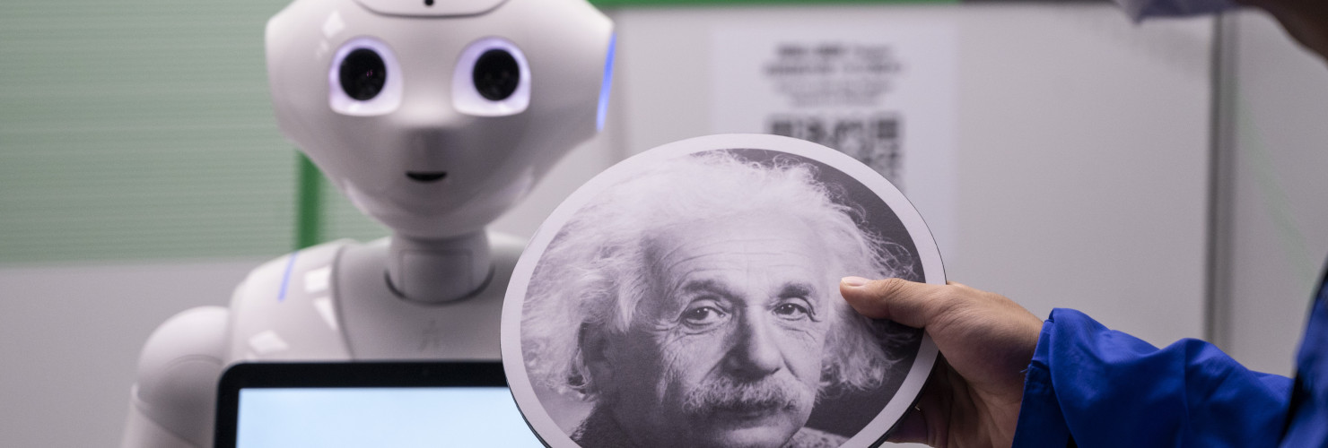 An exhibition staff holds a sign with Albert Einstein headshot to make the robot recognize human faces at a first glance during the 'ROBOTS' exhibition at the Hong Kong Science Museum in Hong Kong on May 8, 2021. 
