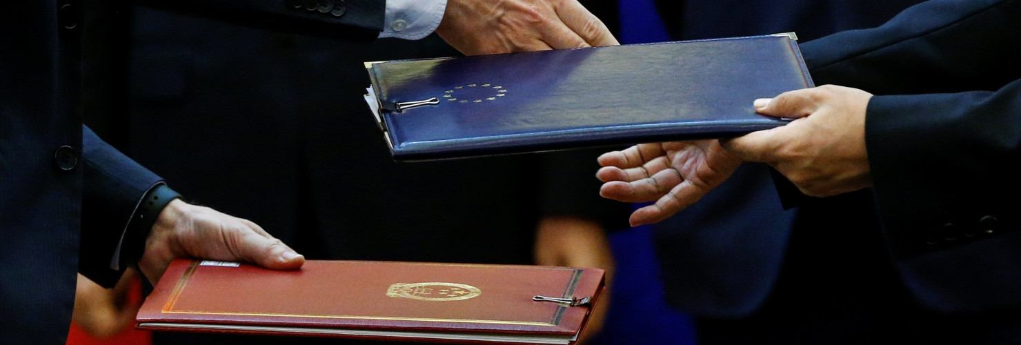 Chinese and European officials exchange documents during a signing ceremony