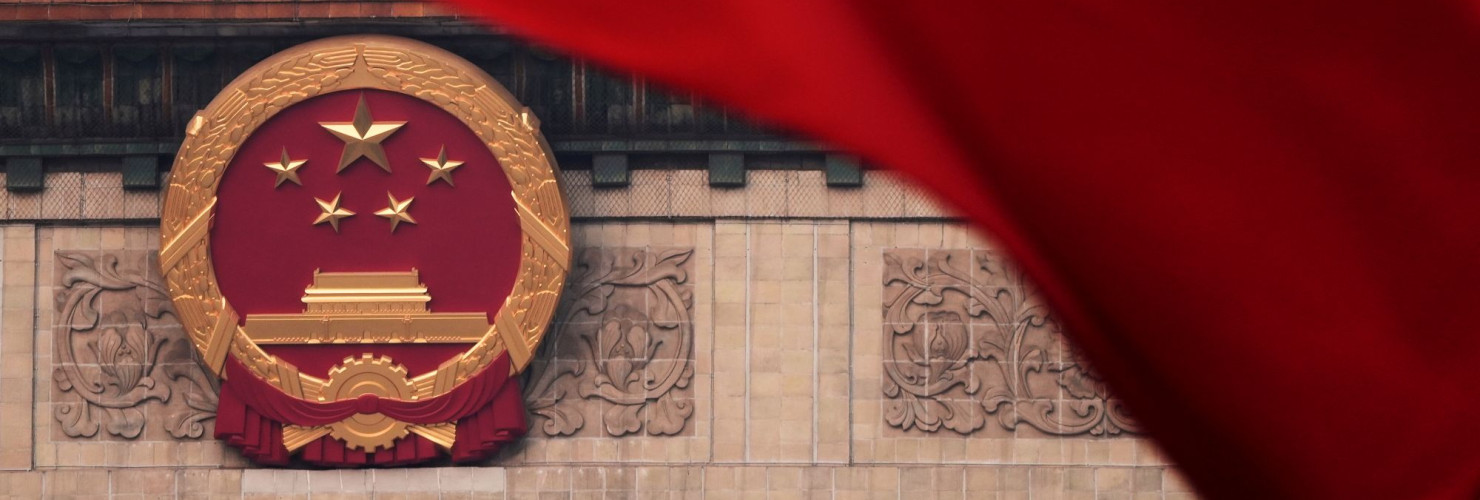 Red flags flutter in the wind near the Chinese national emblem outside the Great Hall of the People during the closing of the Chinese People's Political Consultative Conference in Beijing, Monday, March 10, 2025.