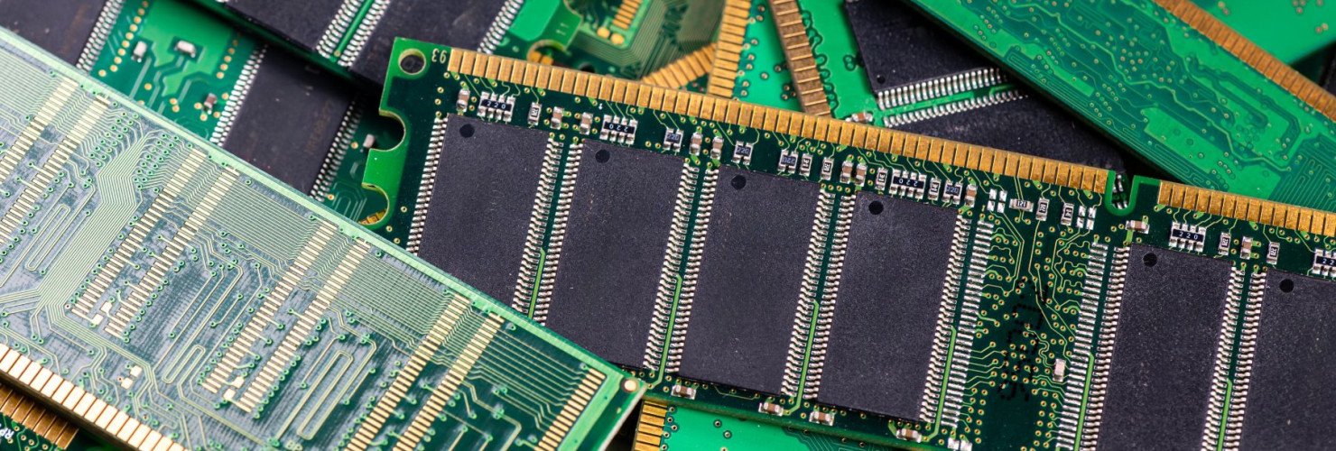 Computer memory modules are piled on a green circuit board, showcasing technology