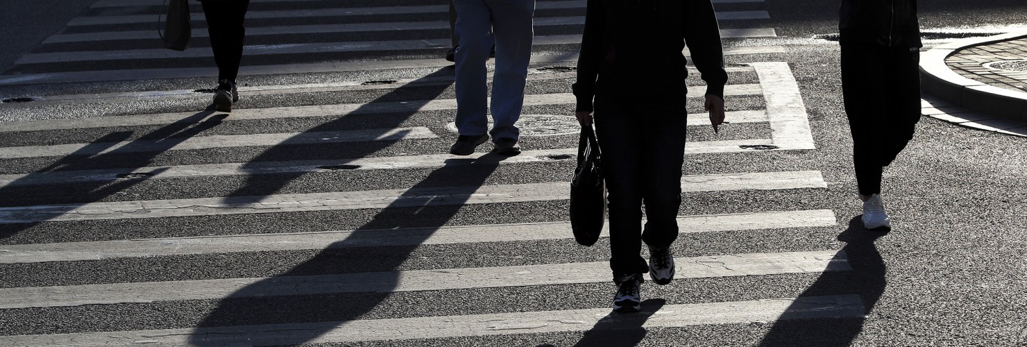 People walk across a street during the morning rush hour in Beijing