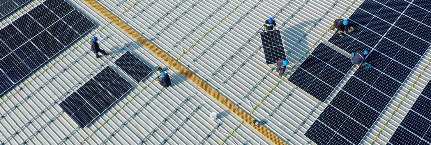 Aerial view of workers installing solar panels on the roof of a plant of China Communications Construction Company (CCCC) Third Harbor Engineering in Zhoushan, Zhejiang Province of China.