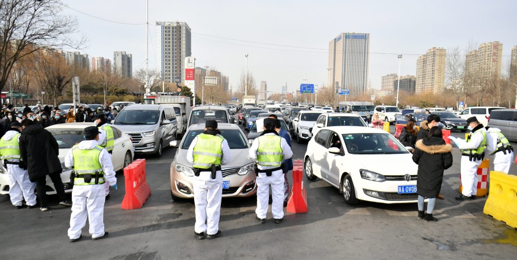 Police officers wearing face masks check drivers' COVID-19 test documentation at an entrance of an expressway