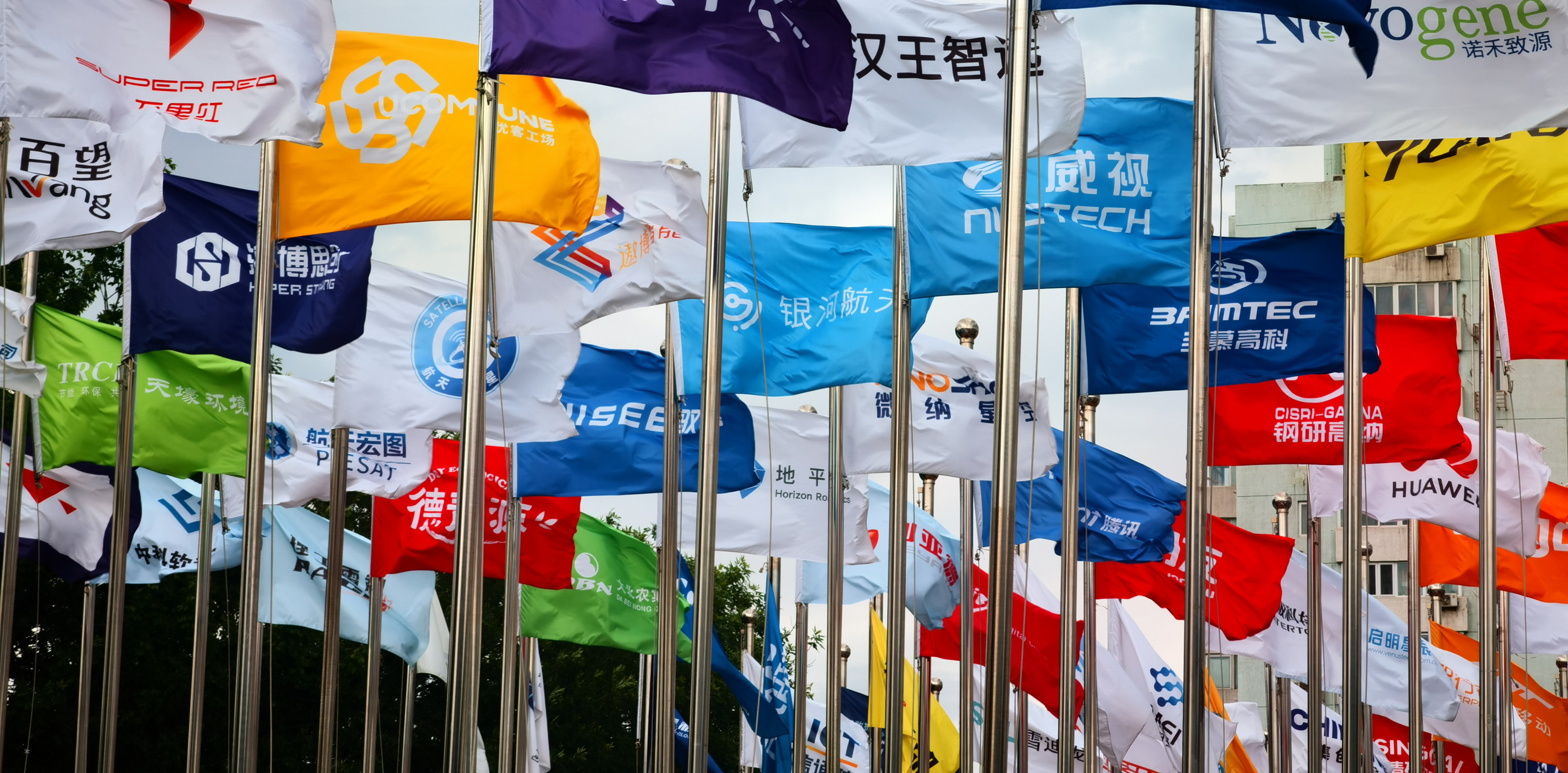 Factory flags of famous Chinese enterprises flutter in the wind under the blue sky in front of the square of the permanent site of the Zhongguancun Forum in Beijing, China, May 14, 2024.