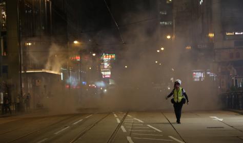 A journalist runs away from tear gas fired on the streets near Lan Kwai Fong, Hong Kong