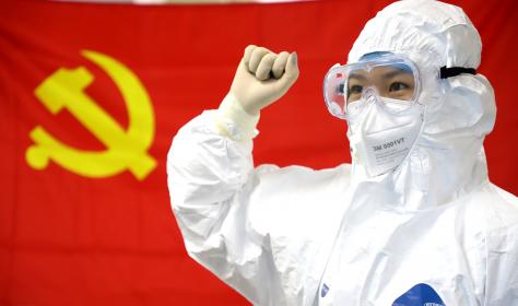 Chinese medical worker in front of a flag of the CCP