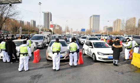 Police officers wearing face masks check drivers' COVID-19 test documentation at an entrance of an expressway