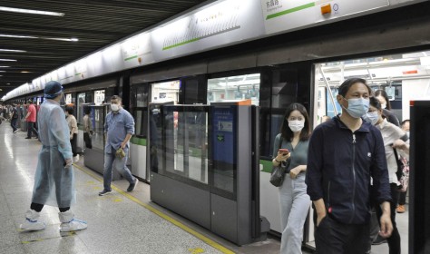 People wearing face masks get on and off a subway train in Shanghai, China