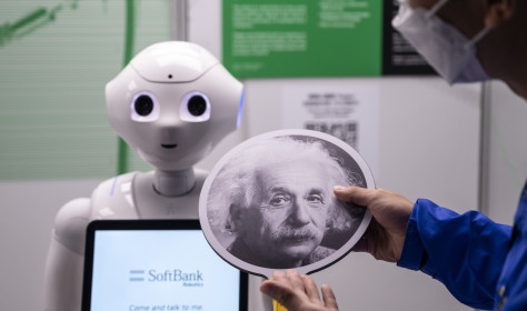 An exhibition staff holds a sign with Albert Einstein headshot to make the robot recognize human faces at a first glance during the 'ROBOTS' exhibition at the Hong Kong Science Museum in Hong Kong on May 8, 2021. 