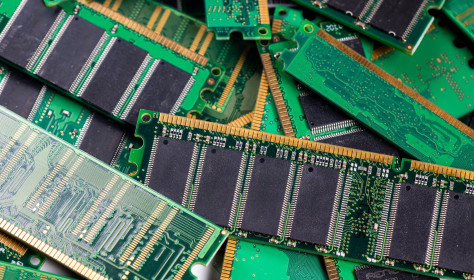 Computer memory modules are piled on a green circuit board, showcasing technology