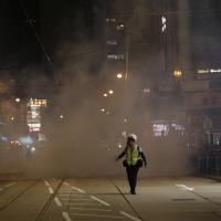 A journalist runs away from tear gas fired on the streets near Lan Kwai Fong, Hong Kong