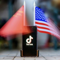 Smartphone showing the Logo of TikTok in front of US and Chinese flags