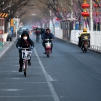 People riding bicycles in a street in Beijing.