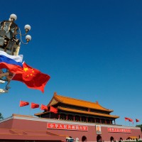 Chinese and Russian national flags flutter on a lamppost in front of Tiananmen