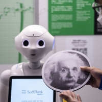 An exhibition staff holds a sign with Albert Einstein headshot to make the robot recognize human faces at a first glance during the 'ROBOTS' exhibition at the Hong Kong Science Museum in Hong Kong on May 8, 2021. 