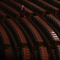 A hostess gives a final check on the reports placed on tables ahead of the closing session of the National People's Congress (NPC) at the Great Hall of the People in Beijing, Monday, March 11, 2024. 