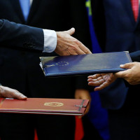 Chinese and European officials exchange documents during a signing ceremony 