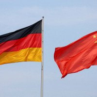 The flags of Germany and China are flying in the wind.