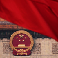 Red flags flutter in the wind near the Chinese national emblem outside the Great Hall of the People during the closing of the Chinese People's Political Consultative Conference in Beijing, Monday, March 10, 2025.