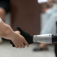 A general view shows a handshake between a human and a humanoid robot at the Shanghai New Expo Center during the opening day of the World Artificial Intelligence Conference (WAIC) 2025 in Shanghai, China, on July 26, 2025.