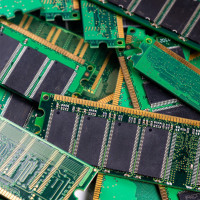 Computer memory modules are piled on a green circuit board, showcasing technology