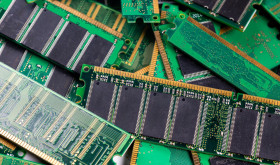 Computer memory modules are piled on a green circuit board, showcasing technology