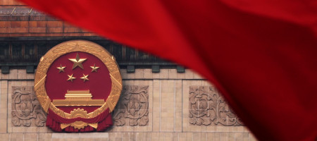 Red flags flutter in the wind near the Chinese national emblem outside the Great Hall of the People during the closing of the Chinese People's Political Consultative Conference in Beijing, Monday, March 10, 2025.