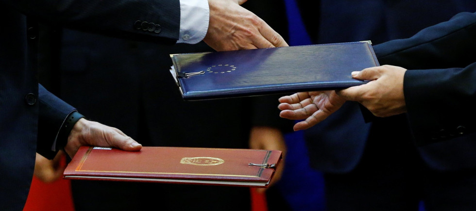 Chinese and European officials exchange documents during a signing ceremony 