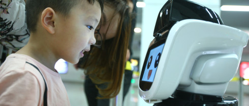A boy looks at the intelligent robot "Xiaogui" at Yinghua Park metro station in Ningbo, Zhejiang Province.
