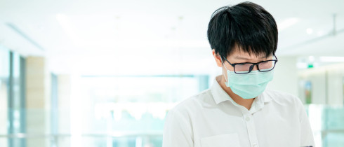A man wearing a facemask looks at his smartphone
