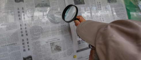 An elderly person reads a newspaper with magnifying glasses that says 'Progress made in the research and development of China's new aircraft carrier' in Beijing, China, 04 August 2022.