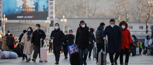 Passengers wearing face masks walk with their luggage in front of the Beijing Railway Station in Beijing, China, 10 January 2023.