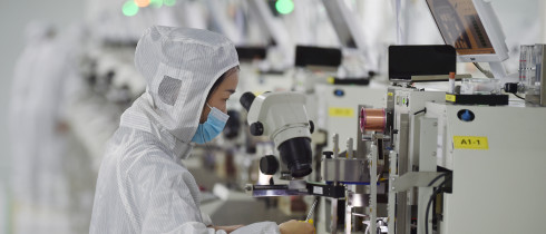 A worker wearing a mask and protective clothing makes chips in a dust-free workshop at a semiconductor company in Suqian, Jiangsu province, China.