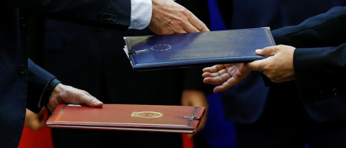 Chinese and European officials exchange documents during a signing ceremony