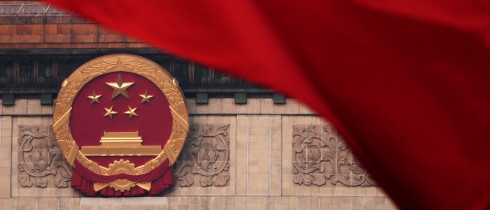 Red flags flutter in the wind near the Chinese national emblem outside the Great Hall of the People during the closing of the Chinese People's Political Consultative Conference in Beijing, Monday, March 10, 2025.