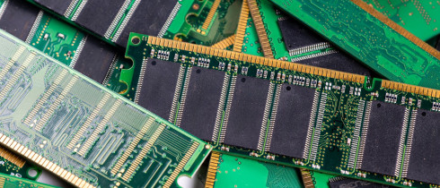 Computer memory modules are piled on a green circuit board, showcasing technology
